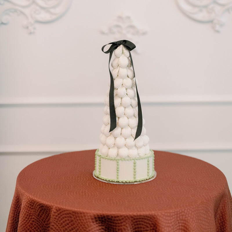 Macaron tower  on a round table with a white wall in the background maca