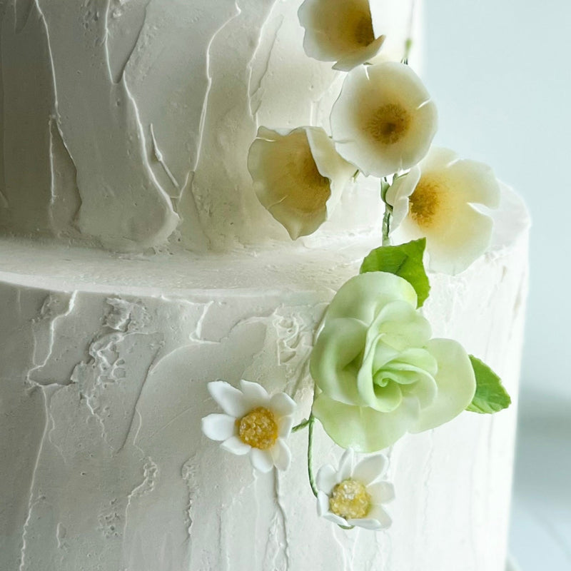 White wedding cake with floral decorations on a light background canlis